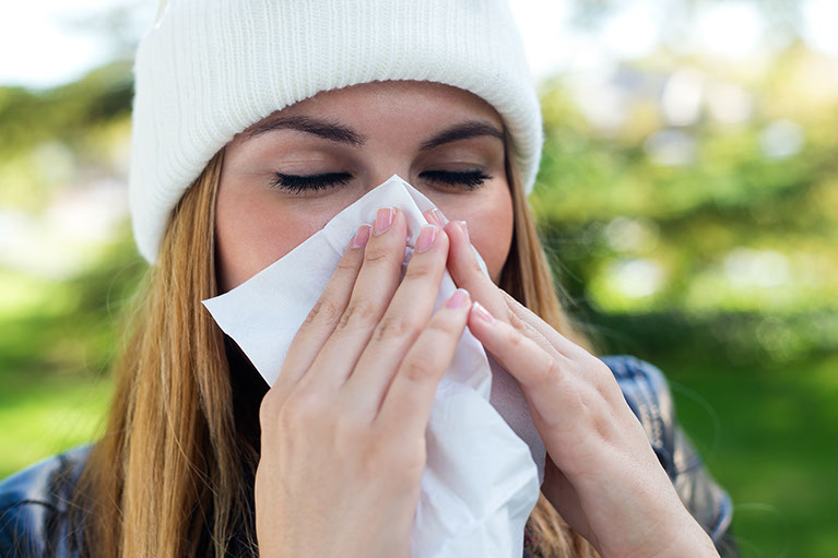 Portrait of beautiful girl with tissue having flu or allergy.